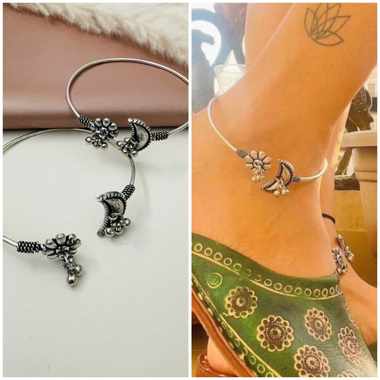 Two silver anklets with a crescent moon and flower design. The anklets are shown on a white background and on a person's ankle.