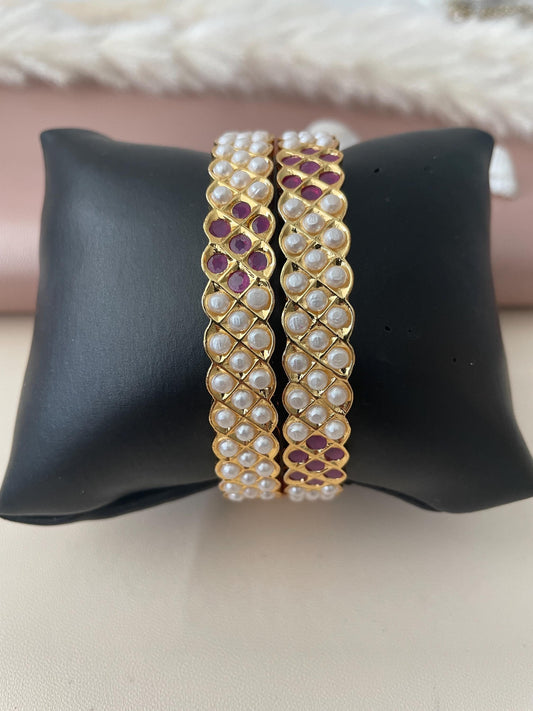 Two gold bangles with white pearl and ruby gemstone embellishments