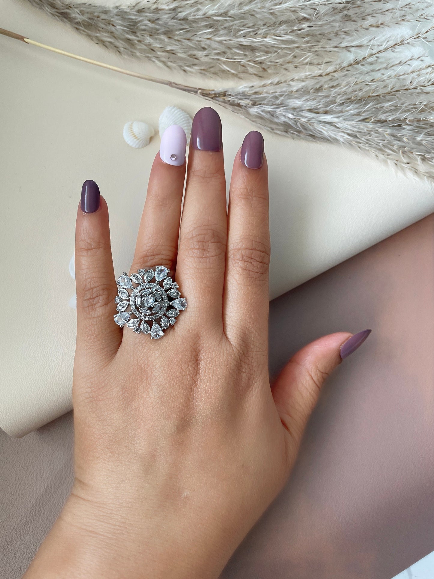Sunning cubic zirconia cocktail stamens ring . A silver ring with a large, round, clear stone surrounded by smaller, clear stones in a floral design.