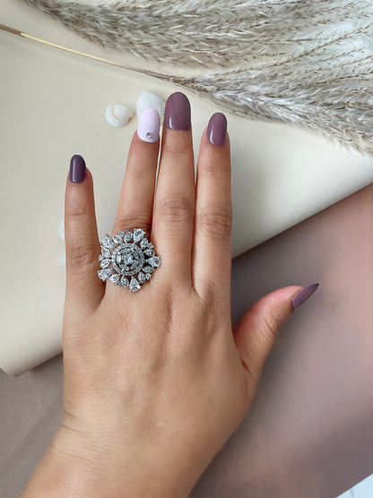 Sunning cubic zirconia cocktail stamens ring . A silver ring with a large, round, clear stone surrounded by smaller, clear stones in a floral design.