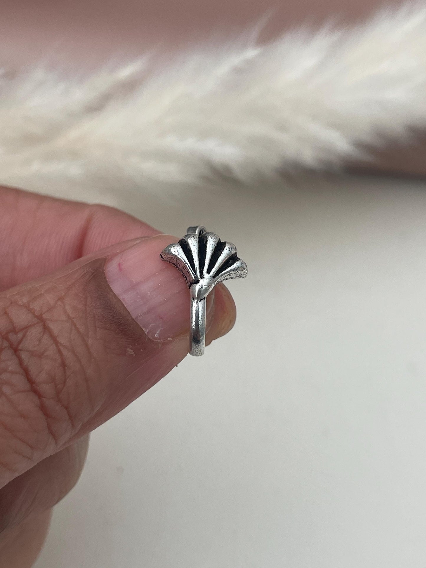 A silver lookalike nose pin with a fan-shaped design