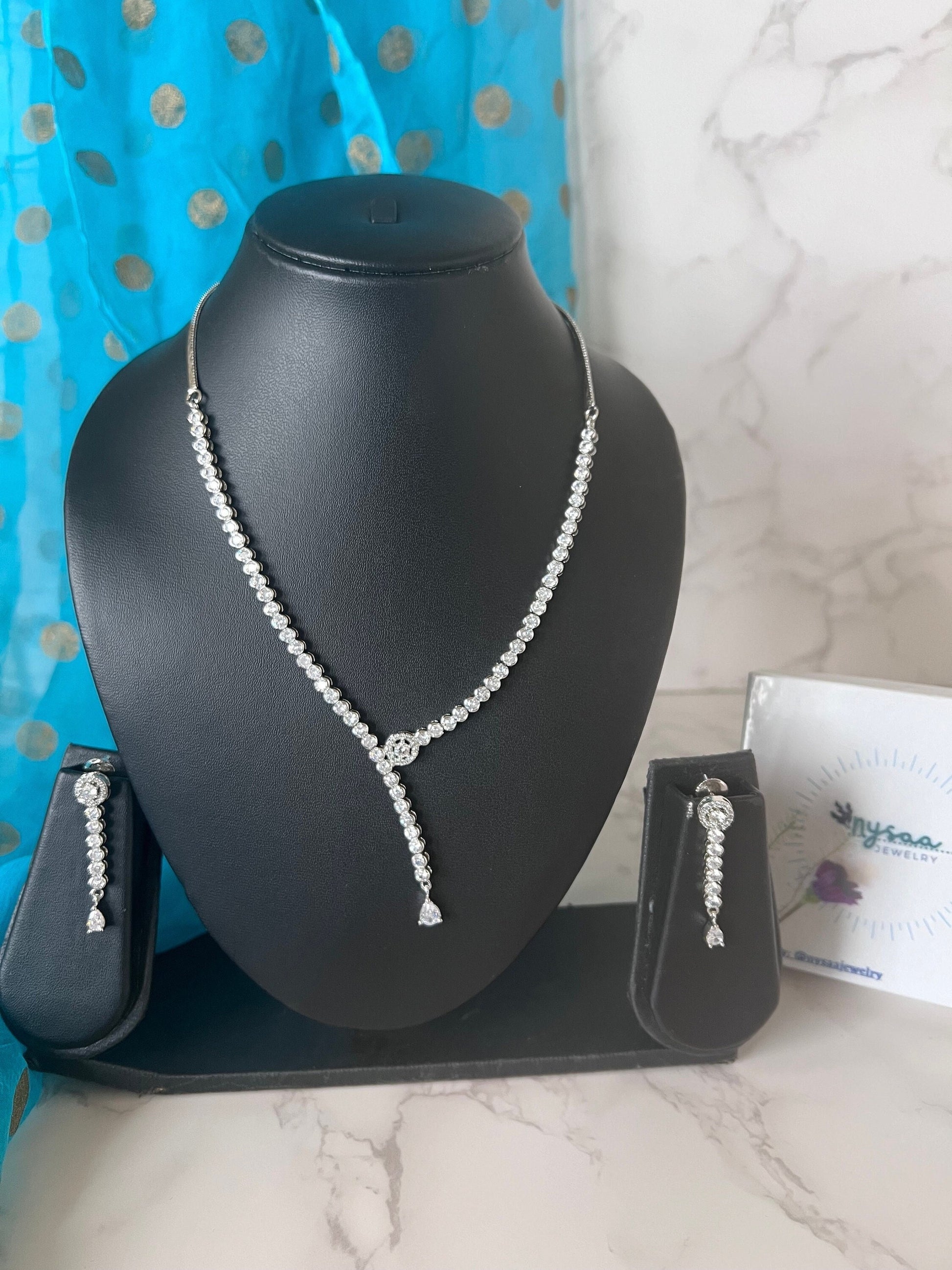 Stunning asymmetrical cubic zirconia necklace set with matching earrings . Rhodium plated perfect for bride , bride mates or mother of bride or groom .