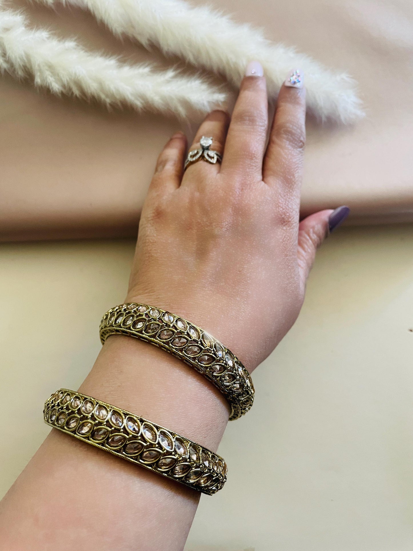 Two gold bangles with clear stones set in a leaf pattern.
