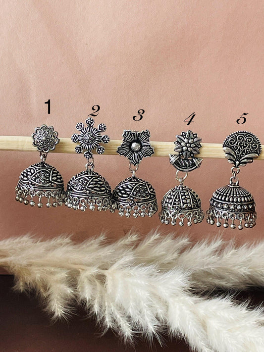 Five pairs of silver earrings with different floral designs. Each earring has a small, round, bell-shaped dangle with a decorative pattern.