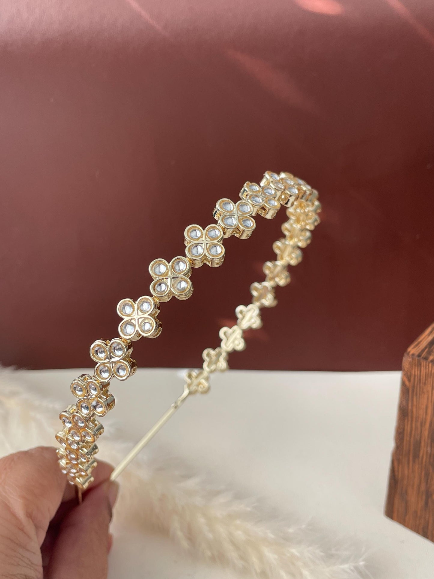 A gold headband with a row of clear rhinestone flower accents.