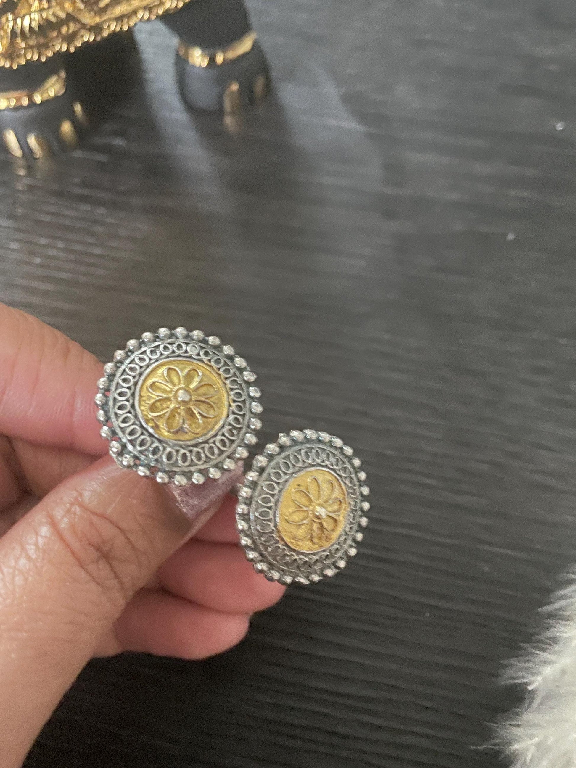 silver and gold finger ring with a floral design. The ring is round and have a beaded edge.