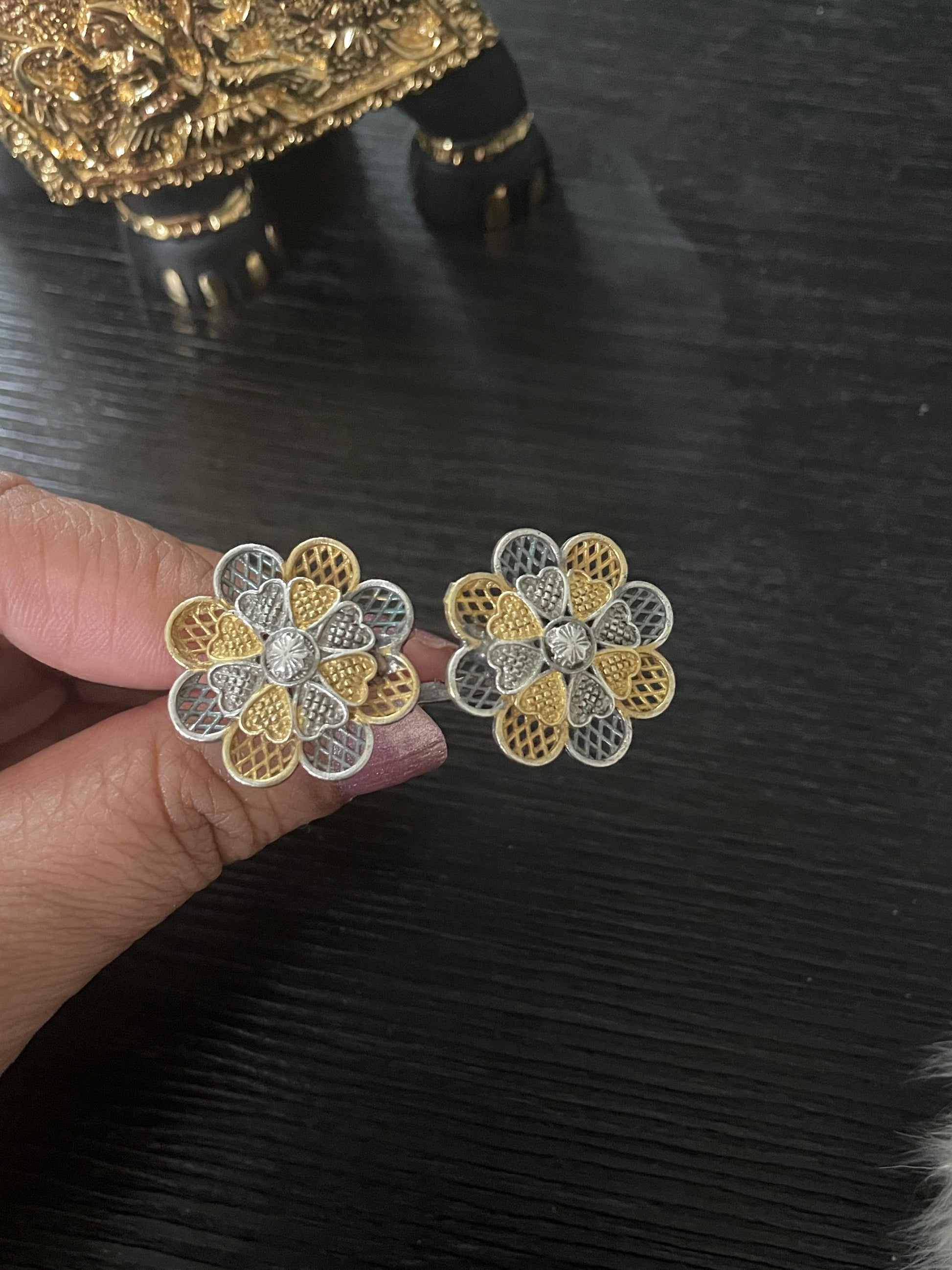 A pair of silver and gold filigree flower-shaped earrings. The finger ring have a delicate design with intricate details.