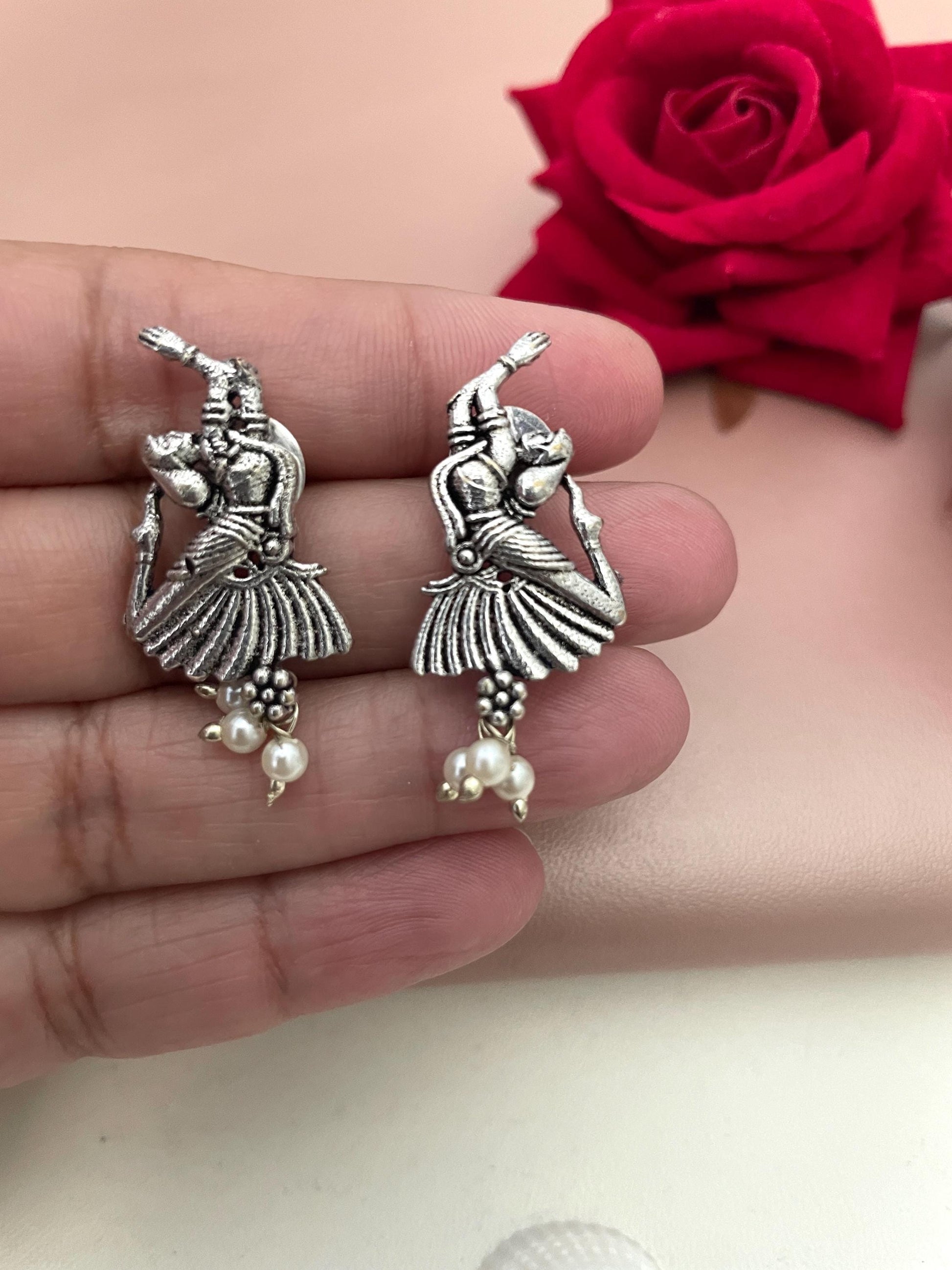 Silver earrings with a detailed design of a woman dancing, accented with small white pearls.