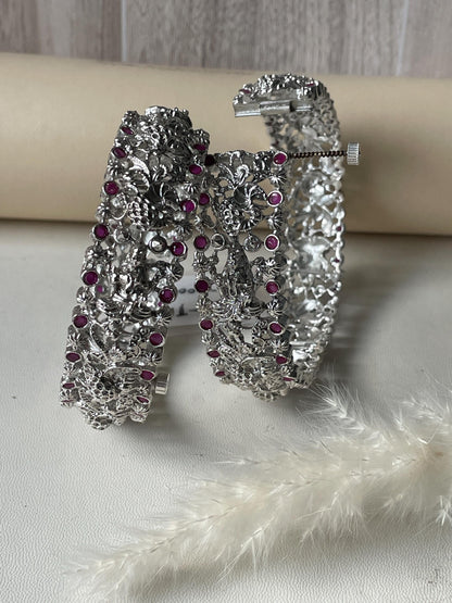 Temple themed silver lookalike openable kada bangles . Intricate detailing with Lakshmi and peacock motif with red gemstones