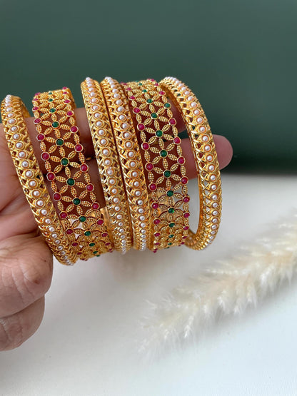 Green and red stone high gold plated bangles with beautiful flower motifs . Comes as set of 6 bangles . 2 flower bangles and 4 pearl bangles