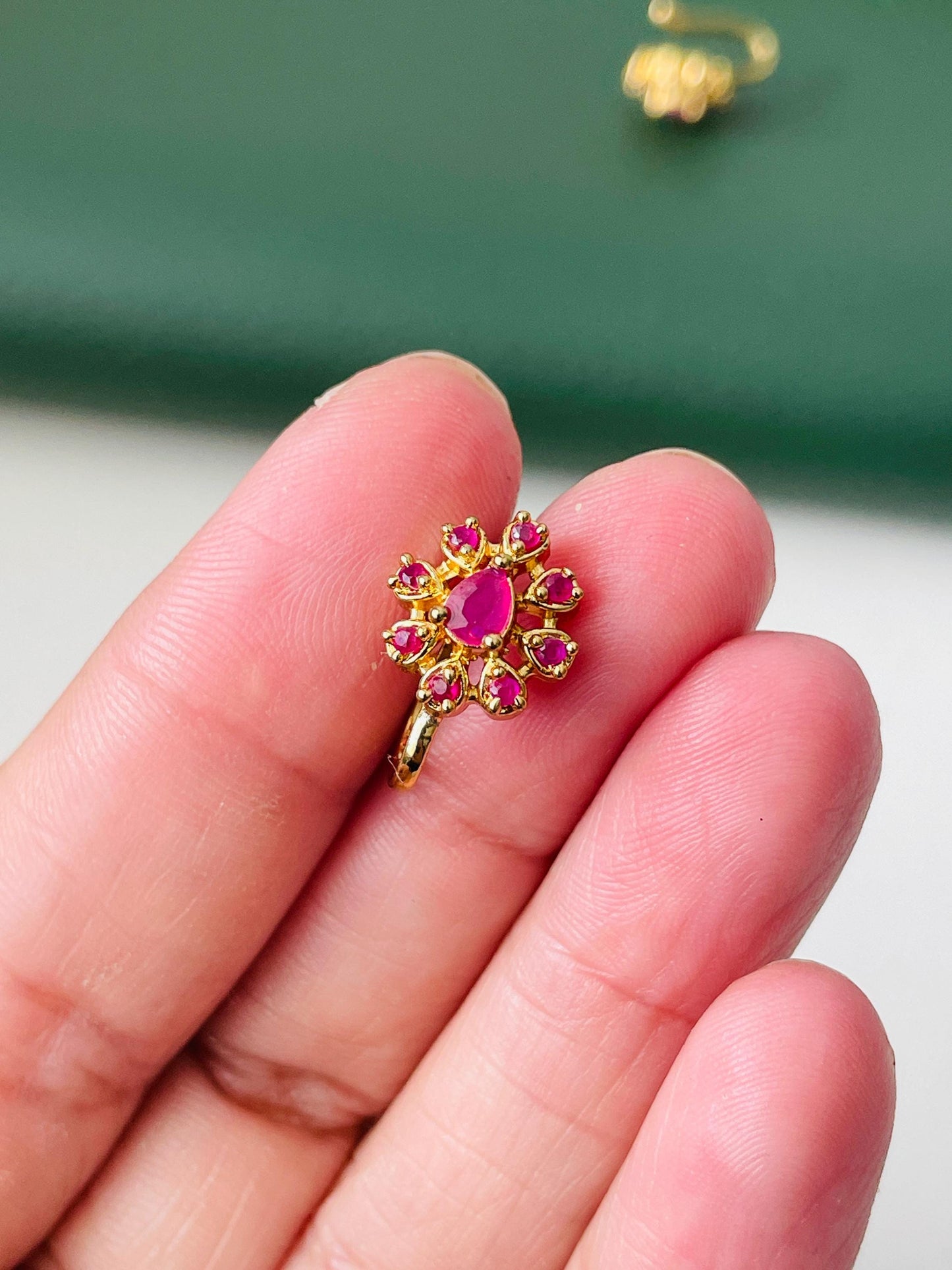 Gold nose ring with a pink ruby stone in the center and smaller pink ruby stones surrounding it.