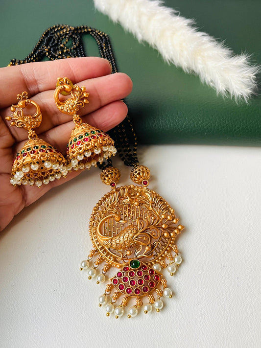 4 strand black beads mangalsutra in temple theme. Peacock motif and decorated with Ruby and green stones. Comes with equally stunning jhumkis .
